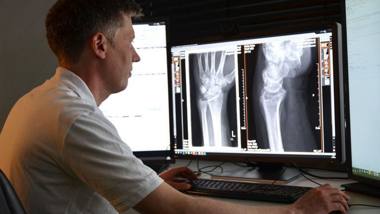 Arzt schaut sich Röntgenaufnahmen des Handgelenks auf dem Monitor an, Immanuel Albertinen zentrum für Radiologie, Standort Hamburg-Schnelsen