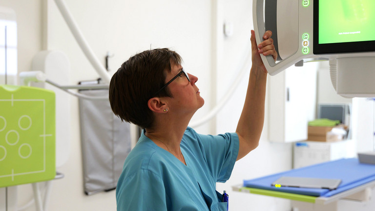Eine medizinische Mitarbeiterin nimmt Einstellungen an einem radiologischen Gerät vor, Immanuel Albertinen Zentrum für Radiologie, Standort Hamburg-Schnelsen